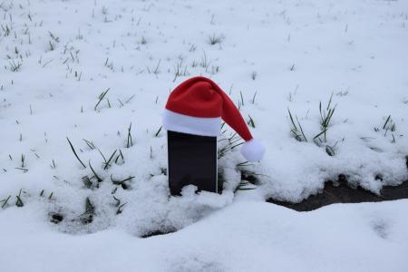 Smartphone mit roter Mütze im Schnee