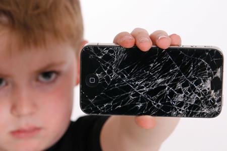 Kleiner Junge mit einem defekten Smartphone in der Hand