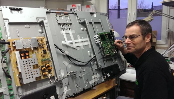 Techniker in der Werkstatt mit Fernseher