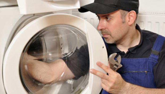Techniker hantiert an einer Waschmaschine
